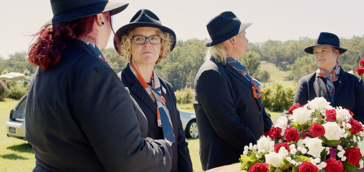 funeral directors gathered around a coffin
