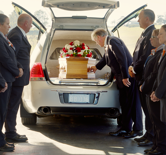 funeral director transferring a coffin into a hearse