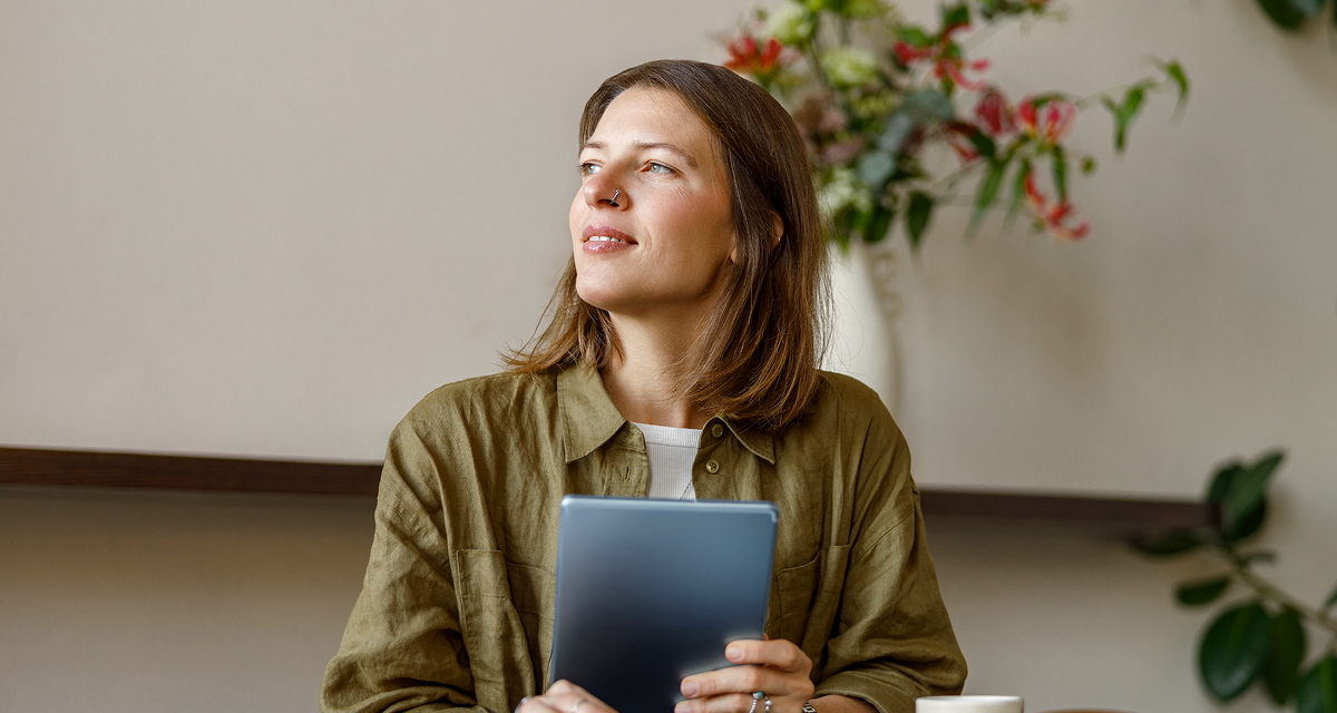 woman holding a tablet while looking into the distance
