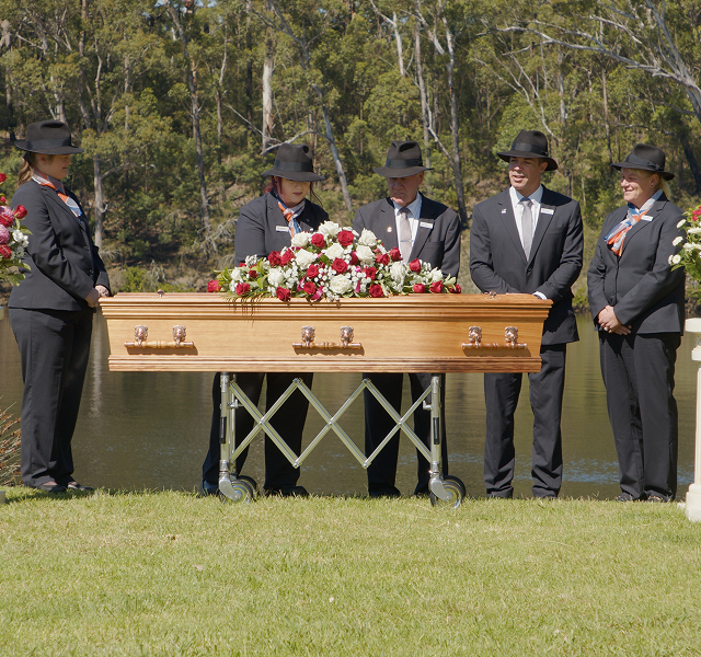 funeral directors gathered around a coffin along the river