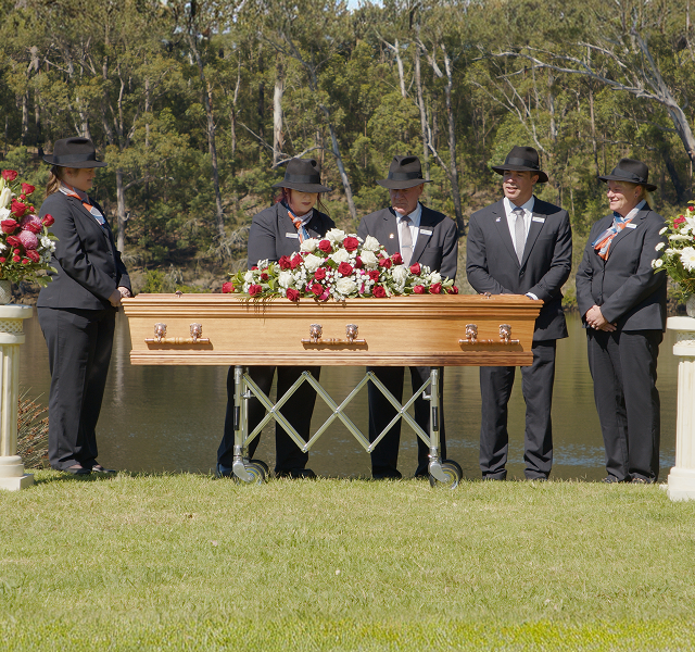 funeral directors gathered around a coffin